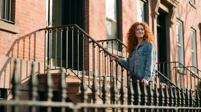 Generated portrait of a red-haired woman in a denim jacket on a stoop, styled like a street photograph